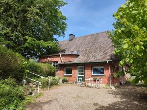 ein rotes Backsteinhaus mit einem Tisch und Stühlen in der Unterkunft Reiterhof - Welsh Cob Gestüt in Kasseedorf