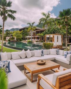 um pátio com um sofá, uma mesa e uma piscina em L'Escale Resort Marina & Spa - Small Luxury Hotels of the World em Mahé