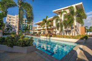 a swimming pool in front of a building with palm trees at 8 Spatial - ForeverMC Condotel 2BR 5615 in Davao City