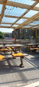 un grupo de mesas de picnic bajo un dosel de madera en Croppers Arms en Huddersfield