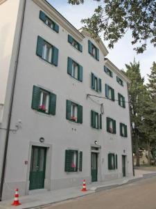 a white building with green shutters and flowers in the windows at In2theRooms in Punat