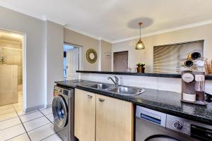 uma cozinha com um lavatório e uma máquina de lavar roupa em Westpoint Executive Suites, Sandton, Johannesburg em Joanesburgo