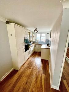 a kitchen with white cabinets and a wooden floor at 2 Priests Mews in Swanage