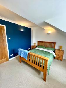 a bedroom with a wooden bed and a blue wall at 2 Priests Mews in Swanage