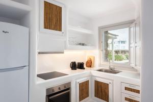 een witte keuken met een wastafel en een raam bij Koumi Homes Mykonos in Ftelia