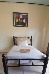 a bed in a bedroom with a picture of flowers at ANUGRAH GILI AIR in Gili Islands