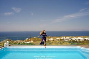a woman standing on the edge of a swimming pool at Dreamland Ηouses in Oia
