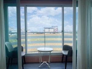 een kamer met een tafel en stoelen en een groot raam bij Jeju Ocean Family Hotel in Jeju-stad