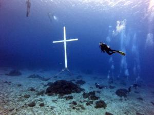 a person in the water next to a cross in the ocean at Oceans Explore Hostel in Green Island