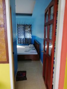 a bathroom with blue walls and a bed and a door at ISLET VIEW Pension House ( Formerly Island View Pension House ) in Oslob