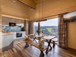 eine Küche und ein Esszimmer mit einem Tisch und einem großen Fenster in der Unterkunft Alpenchalets Oberlaiming in Itter