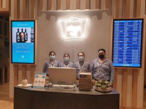 a group of people wearing face masks standing behind a counter at sleep 'n fly Sleep Lounge & Showers, B-Gates Terminal 3 - TRANSIT ONLY in Dubai