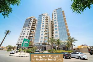 dwa wysokie budynki na parkingu z palmami w obiekcie Mabaat - Obhour - 358 w mieście Dżudda