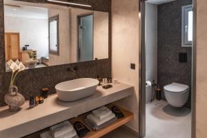 a bathroom with a sink and a toilet and a mirror at Almyra Oia Suites in Oia