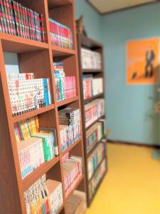een boekenplank gevuld met boeken in een bibliotheek bij ゲストハウス　アンブレラ in Soma