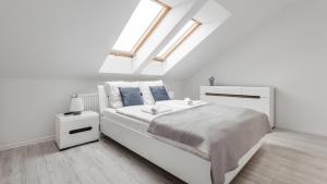 - une chambre blanche avec un grand lit blanc et des lucarnes dans l'établissement Apartamenty Sun & Snow Osiedle Północne, à Darłówko