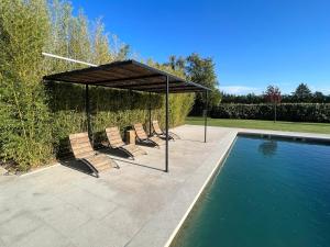 a group of chairs under a canopy next to a swimming pool at Charming Farmhouse in Provence in Cavaillon