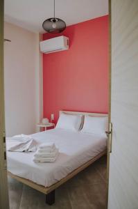 1 dormitorio con cama blanca y pared roja en Blue in Green North, en Kastrosikia
