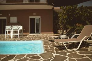 a patio with a pool and chairs and a table at Blue in Green North in Kastrosikia