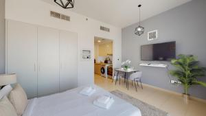 a white living room with a bed and a tv at Primestay - Una Apartment Studio in Town Square in Dubai