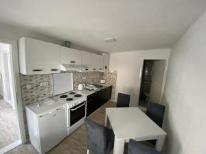 a small kitchen with a stove and a table with chairs at Apartman Downtown in Bosanski Novi