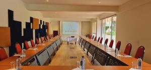 Hotel Boulevard Nairobi, City Centre CBD في نيروبي: قاعة اجتماعات مع طاولات طويلة وكراسي حمراء