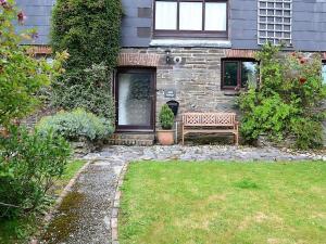 a stone house with a bench in the yard at Mill Cottage in Fowey