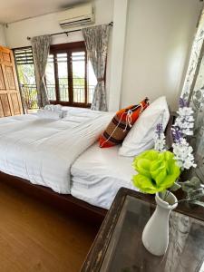Soft Resort Kad Farang Hangdong في Ban Yang Plao: غرفة نوم بسرير وطاولة مع إناء من الزهور