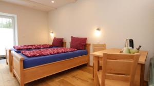 Schlafzimmer mit einem Bett mit roten Kissen und einem Tisch in der Unterkunft Hof Stallegg in Löffingen