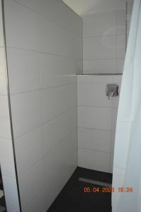 a bathroom with a shower with white tiles at Dolomitenblick in Gerolstein