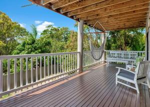 una terraza de madera con 2 sillas y una hamaca en Hibiscus Hideaway, en Valla Beach 3 fotos más