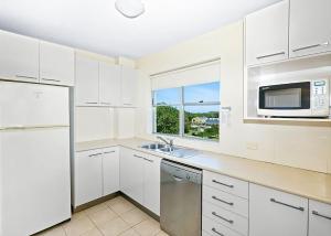 Una cocina blanca con fregadero y microondas. en Sail Away, en Coffs Harbour