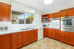 una cucina con armadi in legno, lavandino e finestra di The Lookout a Coffs Harbour