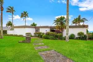 una casa con palmeras y césped verde en The Lookout, en Coffs Harbour