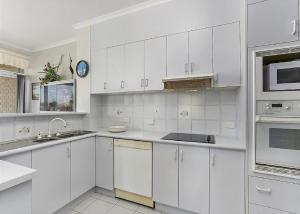a white kitchen with white cabinets and appliances at Solitaire 1 in Sawtell
