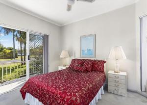 a bedroom with a red bed and a large window at Solitaire 1 in Sawtell