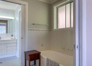 een witte badkamer met een bad en een wastafel bij On the Hillside in Coffs Harbour +5 foto's