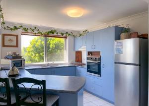 een keuken met blauwe kasten en een witte koelkast bij On the Hillside in Coffs Harbour