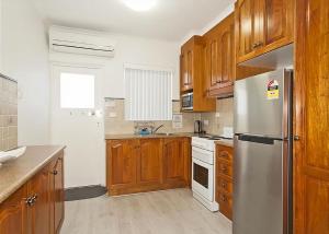 a kitchen with wooden cabinets and a stainless steel refrigerator at Sand Sea 1 in Sawtell