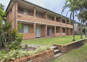 a brick building with a lawn in front of it at Sand Sea 1 in Sawtell