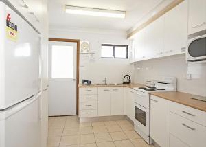 a kitchen with white cabinets and a white refrigerator at Ocean Sands 5 in Sawtell
