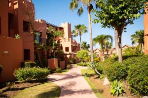 a walkway through a resort with palm trees and houses at Where everyone is welcome in Estepona