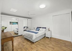 a white bedroom with a bed and a desk at Blue Gem in Sawtell