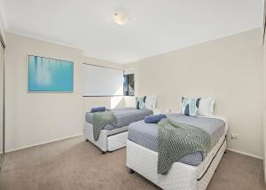 two beds in a room with white walls at Ocean Pines in Nambucca Heads