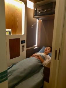 uma pessoa deitada numa cama num quarto de hospital em sleep 'n fly Sleep Lounge, SOUTH Node - TRANSIT ONLY em Doha