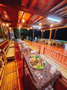 uma sala de jantar com mesas com pratos de comida em A Khoan Homestay - Venuestay em Mai Châu