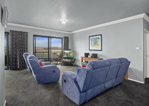 a living room with a blue couch and two chairs at Waters Edge in Nambucca Heads