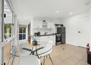 a white kitchen with a table and chairs in it at Garden Spa Villa in Coffs Harbour