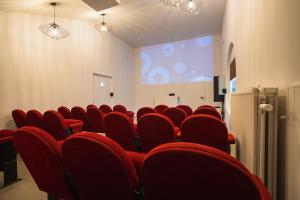 uma sala de conferências com cadeiras vermelhas e um ecrã de projecção em Village du Caillou em Dinant