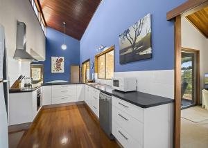 a large kitchen with white cabinets and blue walls at Peninsula in Sawtell